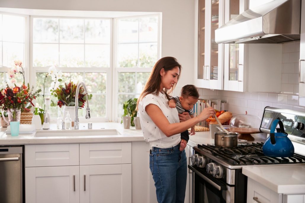 Woman in kitchen holding toddler - Housing market trends 2022